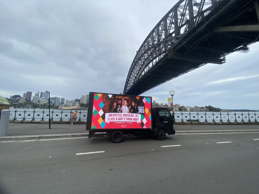 An ad truck parked near the Sydney Harbour Bridge